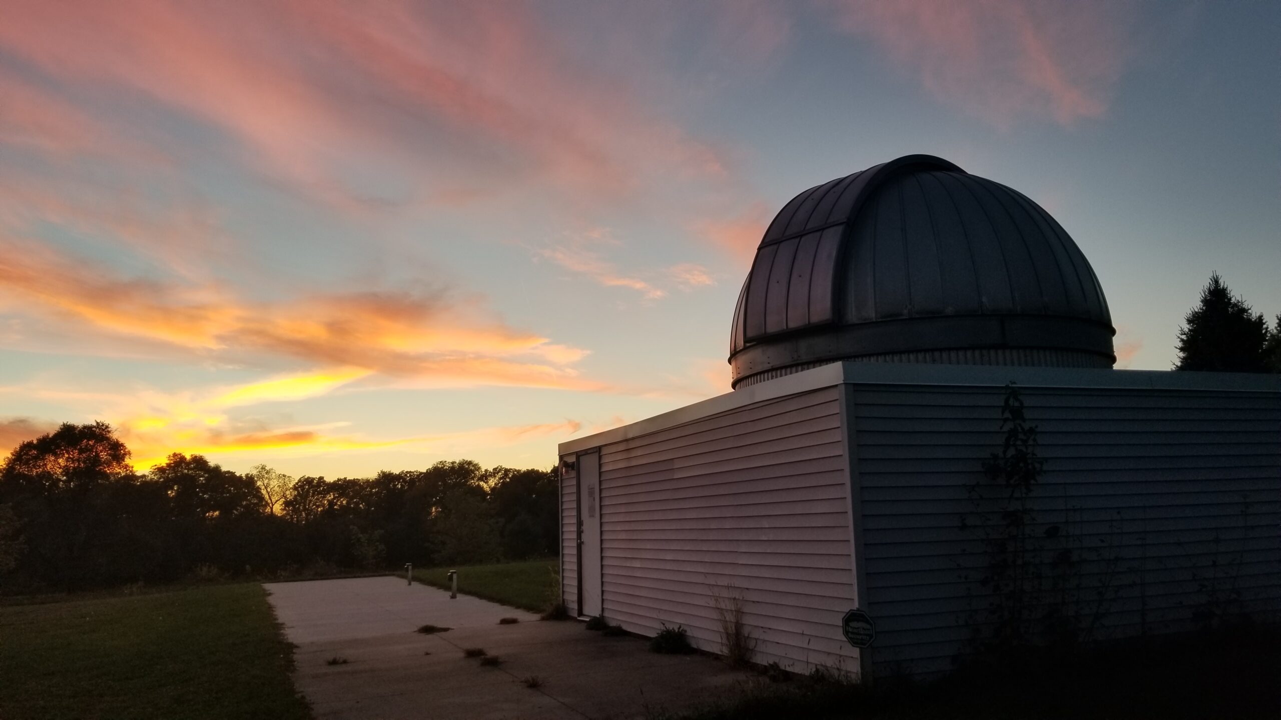 Observatory building from the outside with a sunset in the background.
